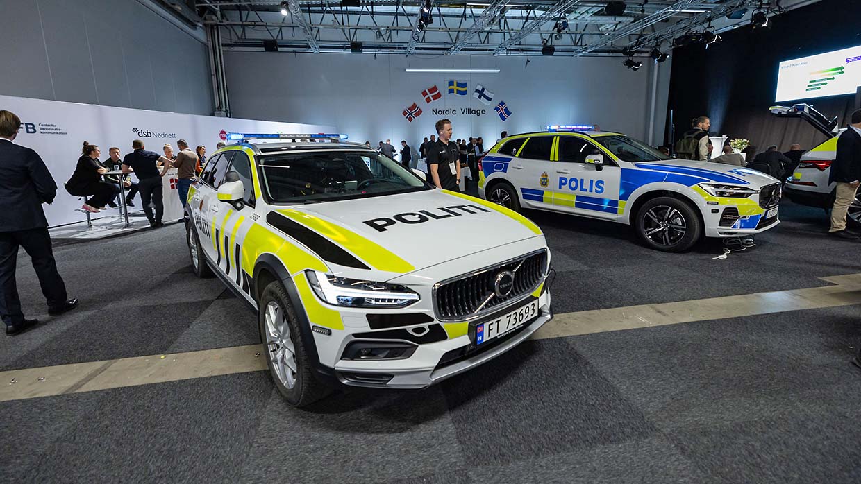 En norsk och en svensk polisbil i en mässhall.